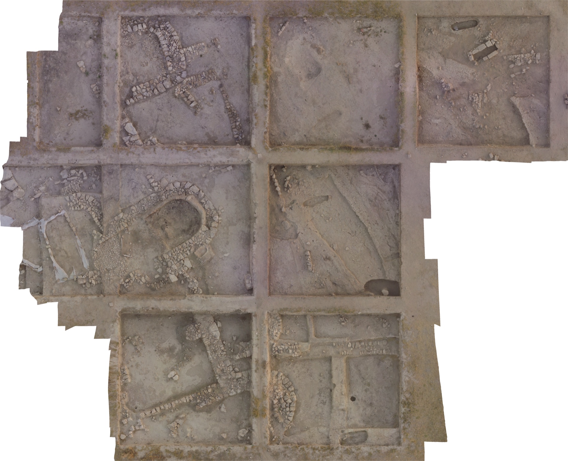 Overhead natural-colour orthophoto of the excavation area: trenches divided into grid squares, stone walls, and the apsidal building at centre.