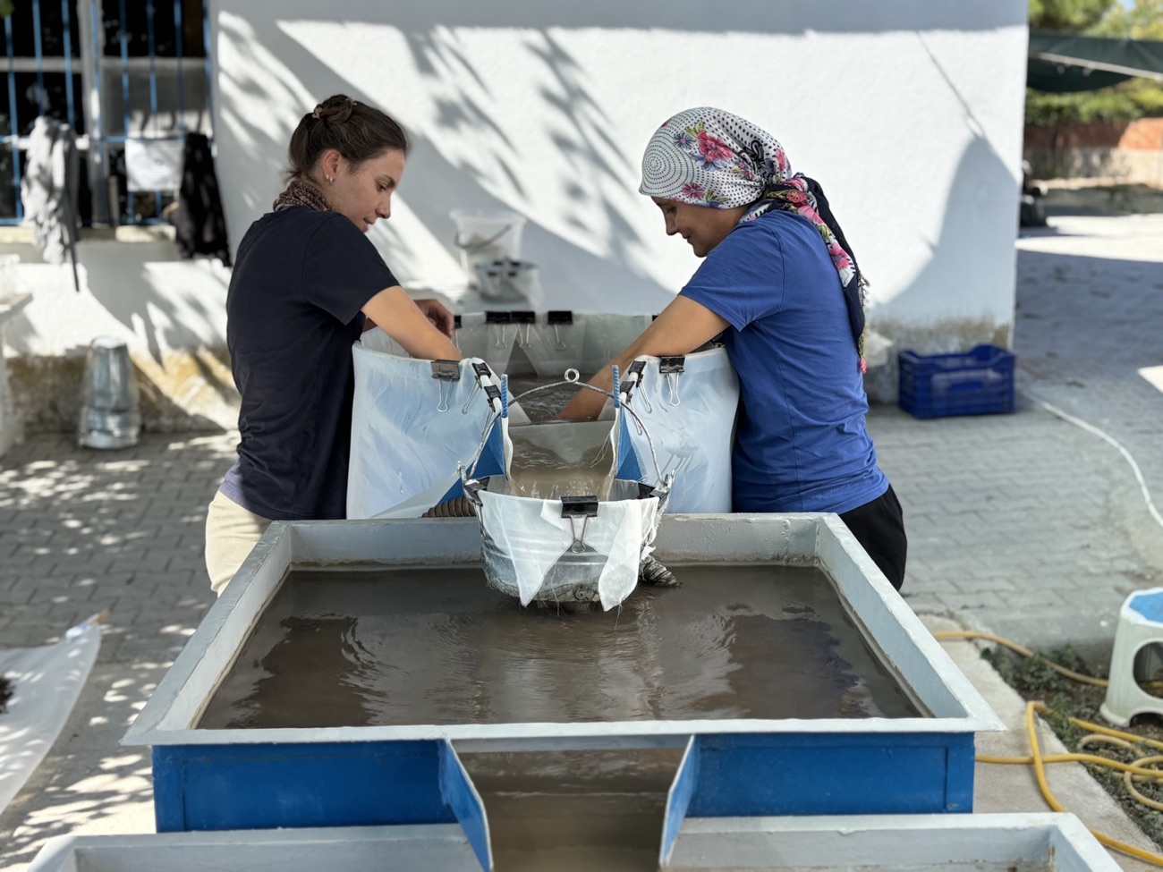 Two team members washing soil samples through a flotation tank.