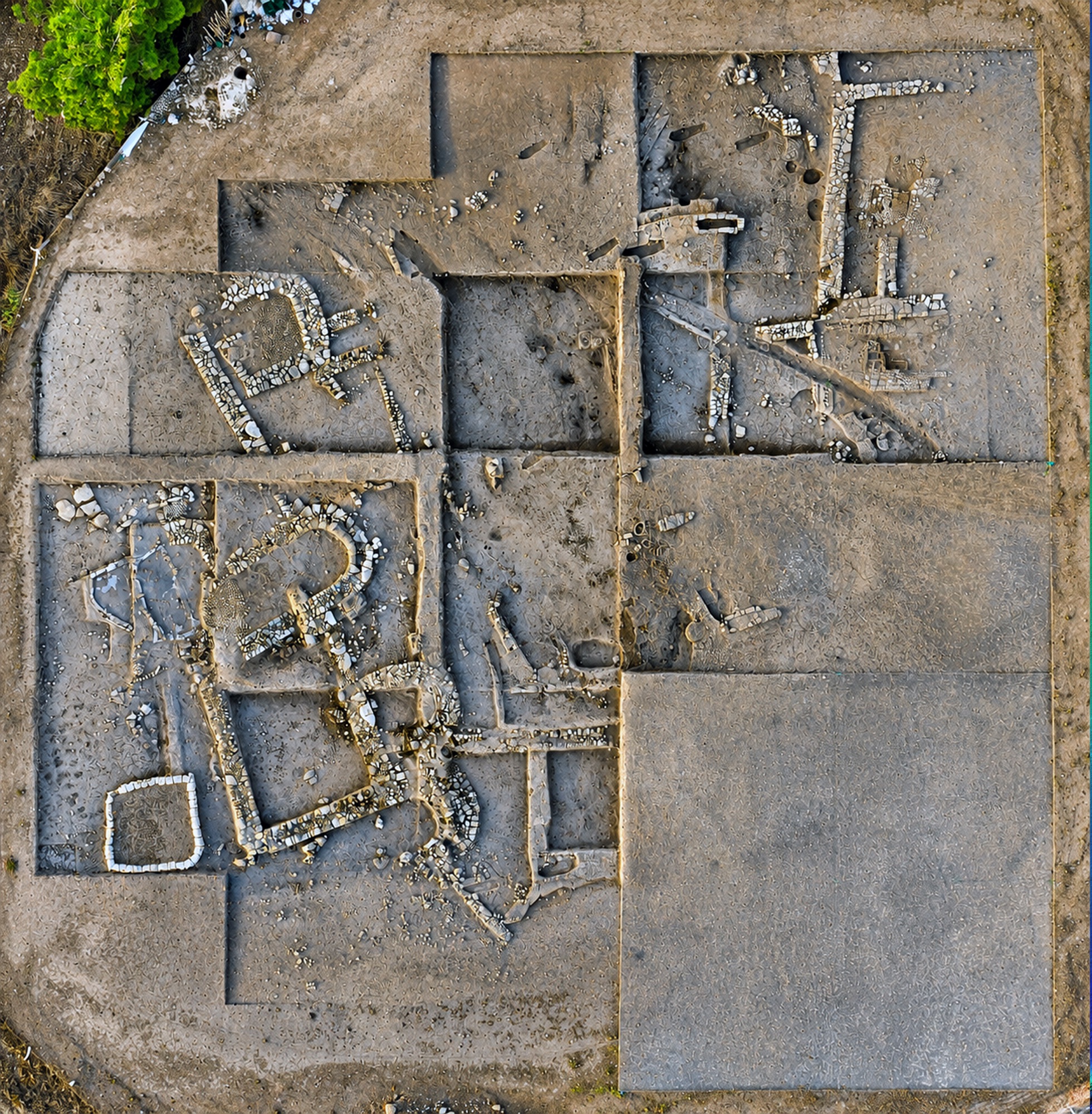Overhead orthophoto of the excavation area: wall remains within trenches divided into grid squares.