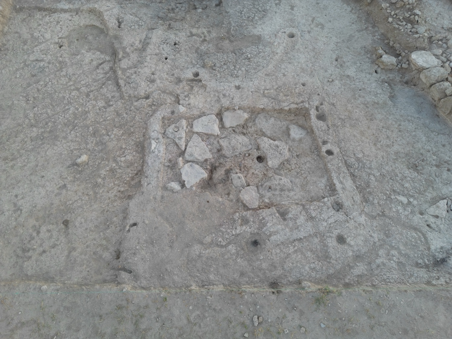A stone-paved rectangular floor exposed in an excavation trench.